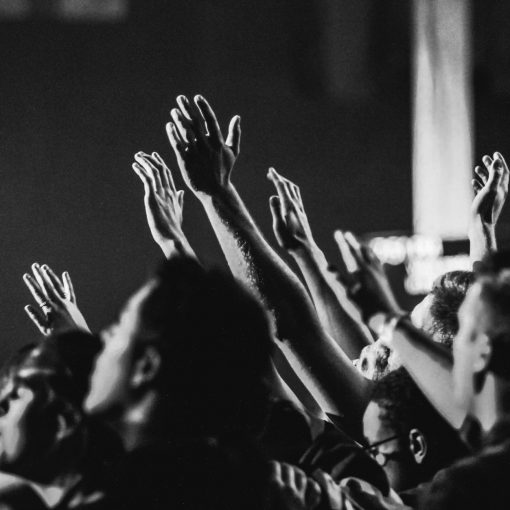 grayscale photo of people raising their hands